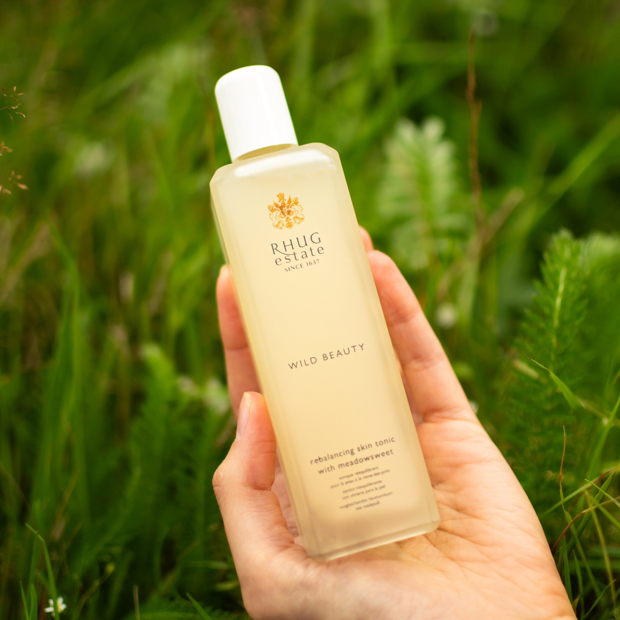 hand holding bottle of organic skin tonic in a field in wales